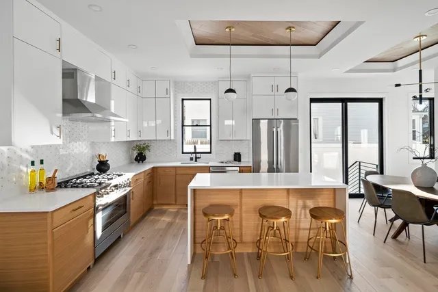 a kitchen with stainless steel appliances granite countertop a refrigerator a sink dishwasher a dining table and chairs with wooden floor