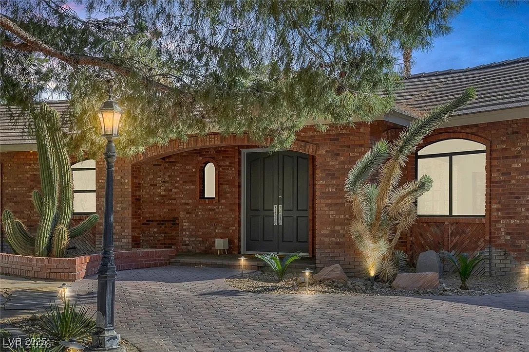 9 Quail Run Road Henderson, NV 89014 - Photo 5 of 57 A welcoming brick facade with mature desert landscaping and paver driveway beckons guests.