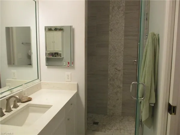 a bathroom with a granite countertop sink a mirror and shower