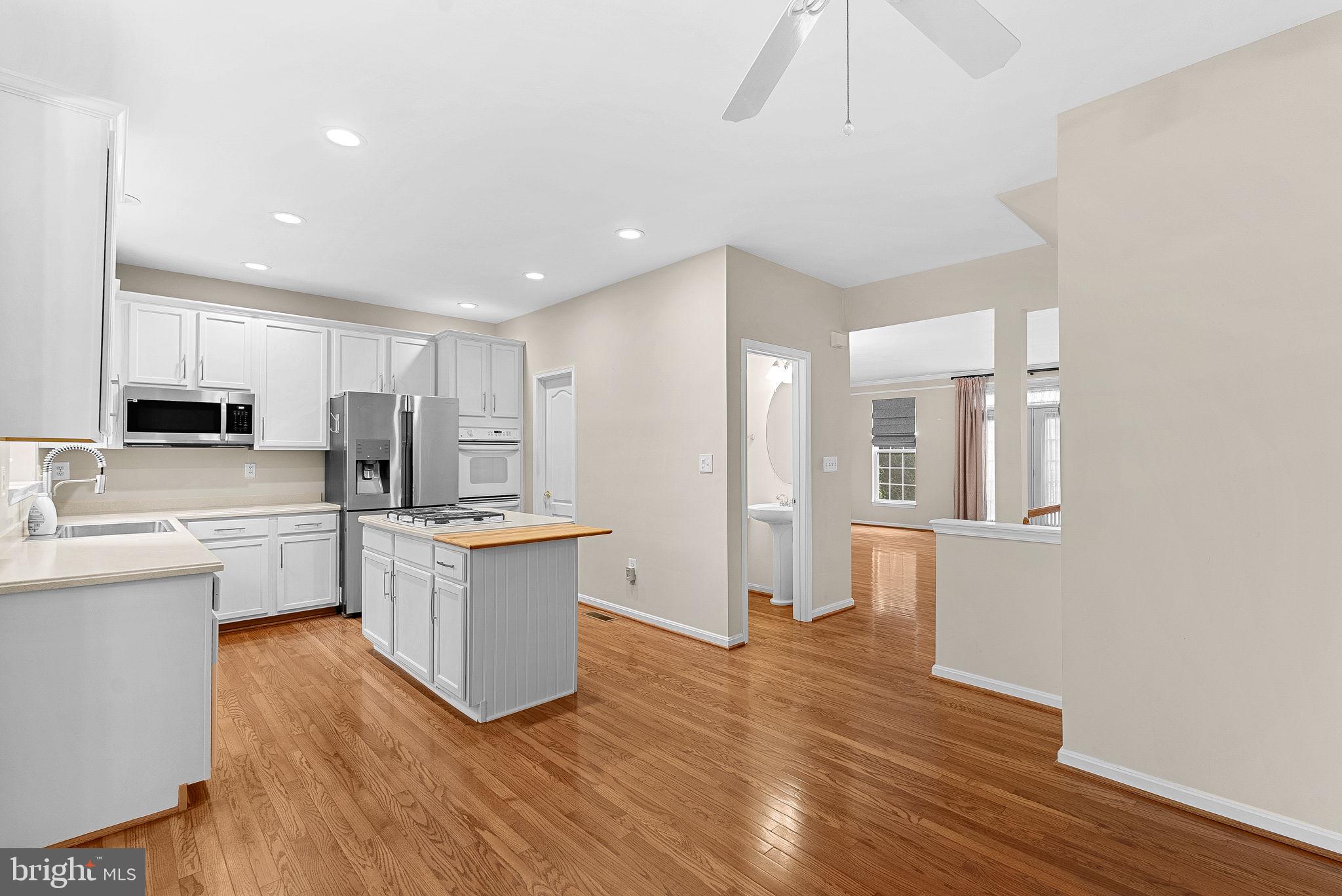 13574 Big Boulder Road Herndon, VA 20171 - Photo 13 of 45 a kitchen with stainless steel appliances granite countertop a refrigerator a sink dishwasher a stove and white countertops with wooden floor