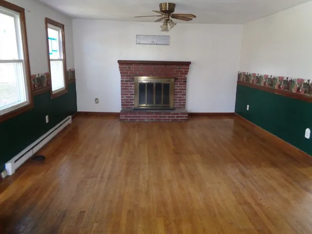 an empty room with windows fireplace and wooden floor