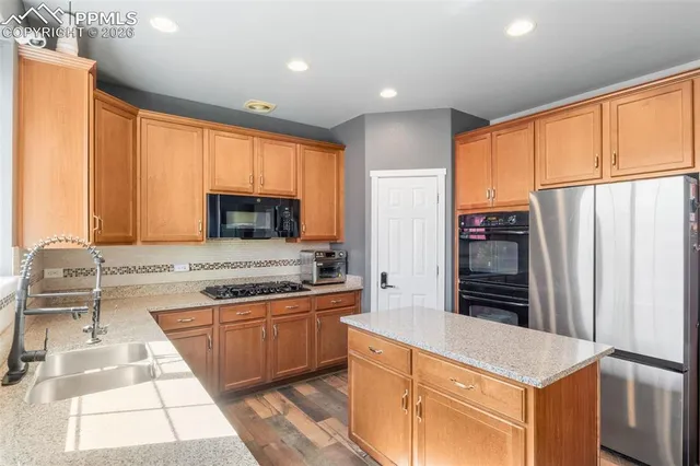 a kitchen with stainless steel appliances granite countertop a refrigerator and a stove top oven