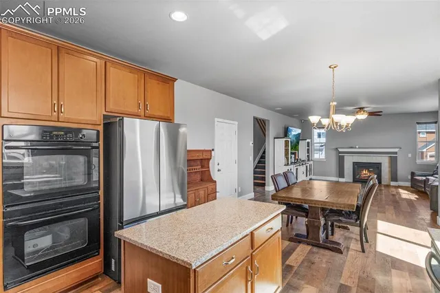 a large kitchen with granite countertop a table chairs stainless steel appliances and cabinets