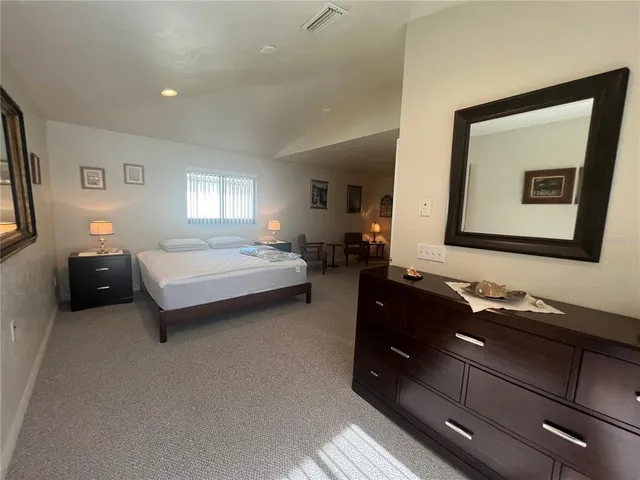 a spacious bedroom with a bed and a dresser