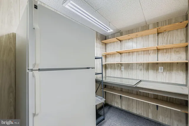 a view of backyard of white apartments with large trees and wooden fence