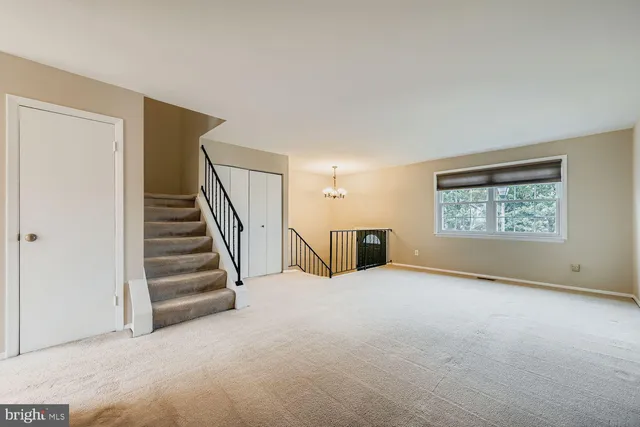 a view of an empty room with stairs and a window