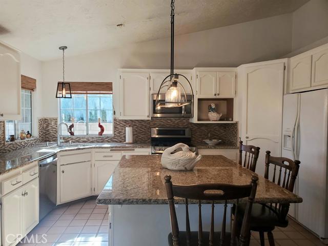 a kitchen with kitchen island a dining table chairs sink and cabinets