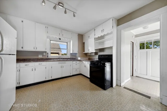 a kitchen with granite countertop white cabinets and refrigerator