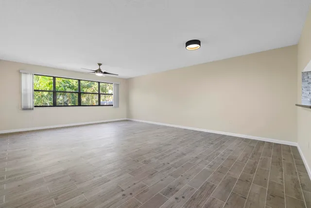 a view of empty room with wooden floor and ceiling fan