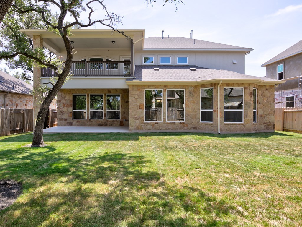 4303 Logan Ridge Drive Cedar Park, TX 78613 - Photo 24 of 24 Stone exterior rear elevation featuring a covered second-story balcony with balustrade and a ground-level concrete patio