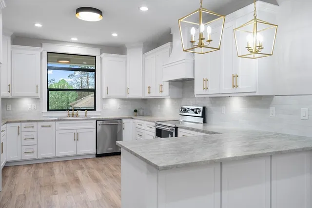 a kitchen with stainless steel appliances granite countertop white cabinets granite counter tops and a hard wood floors