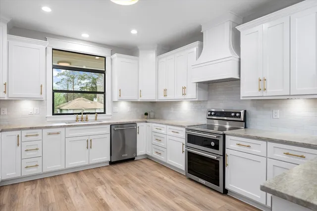 a kitchen with stainless steel appliances granite countertop a stove and white cabinets