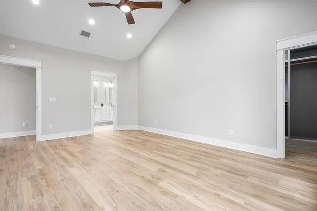 an empty room with wooden floor ceiling fan and windows
