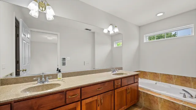 a bathroom with a sink double vanity granite tub and a mirror