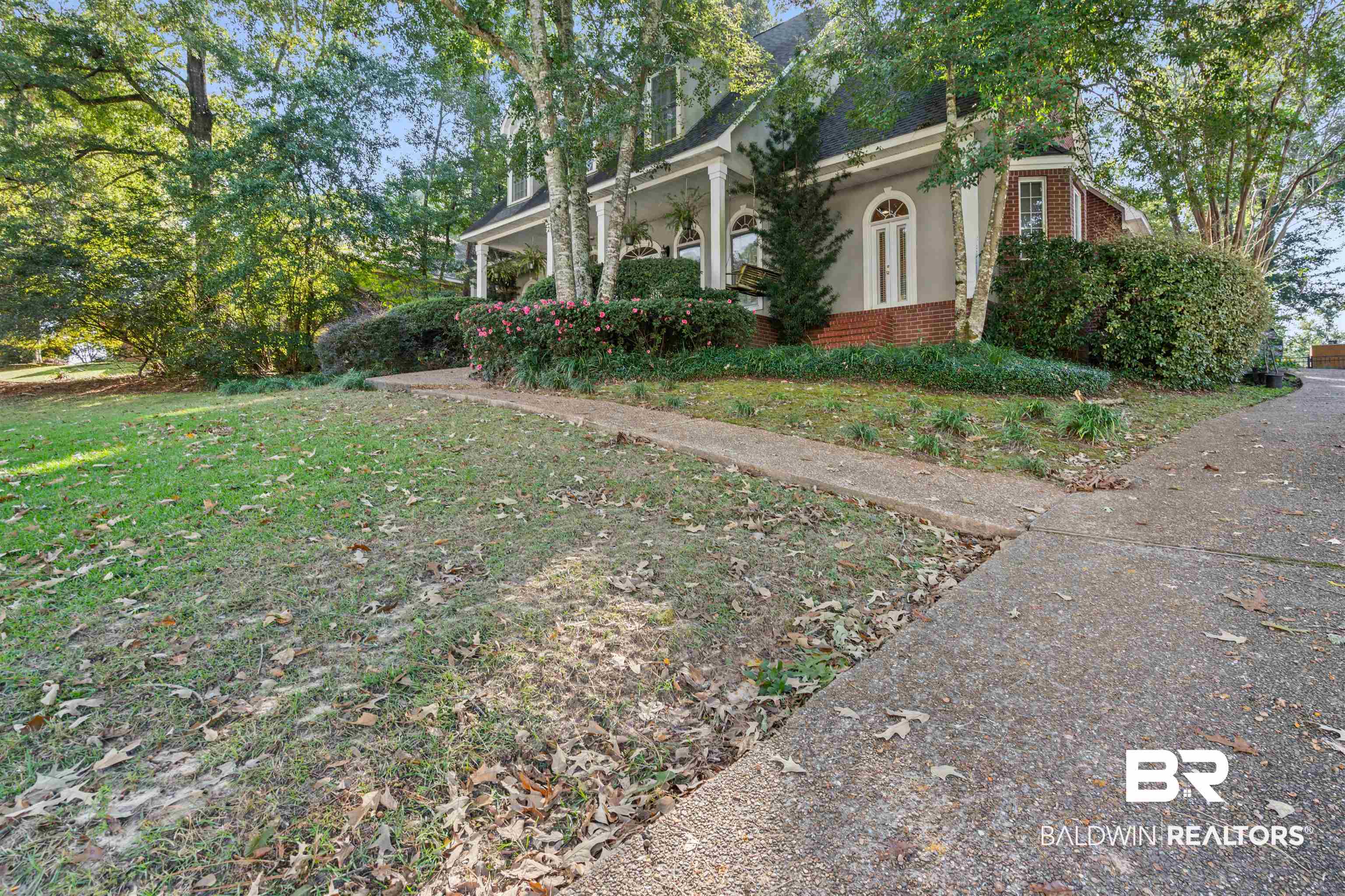107 Beaver Dam Road Fairhope, AL 36532 - Photo 32 of 45 View of home's exterior featuring brick siding, stucco siding, covered porch, and a lawn