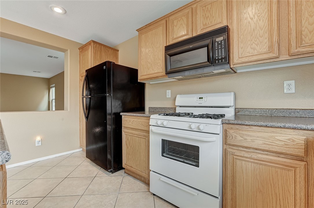 83 Lockheed Avenue Las Vegas, NV 89183 - Photo 12 of 28 Kitchen featuring black appliances, light tile patterned floors, and light brown cabinets