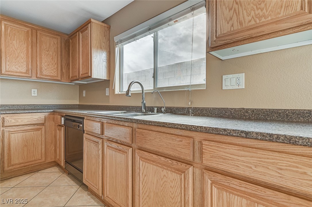 83 Lockheed Avenue Las Vegas, NV 89183 - Photo 8 of 28 Kitchen featuring dark countertops, light tile patterned floors, dishwasher, and light brown cabinetry