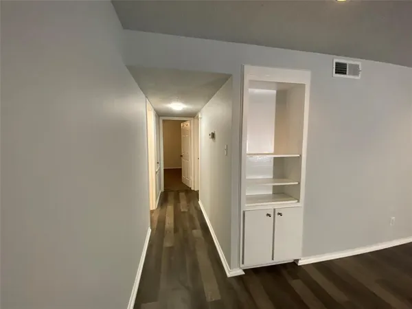 a view of a hallway with wooden floor and closet