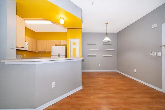 a view of a kitchen with a fridge and wooden floor
