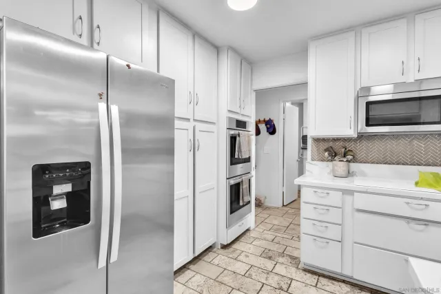 a kitchen with white cabinets and refrigerator