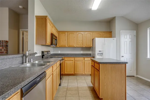 a kitchen with stainless steel appliances granite countertop a sink and a refrigerator