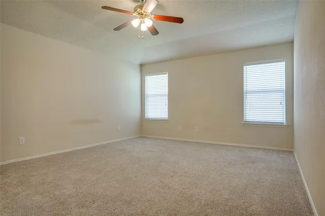 an empty room with windows and fan