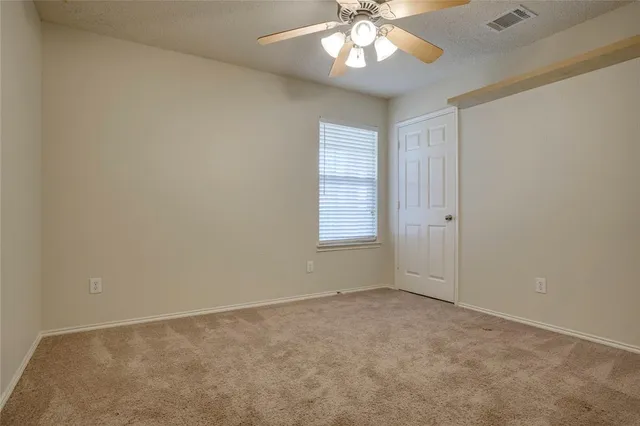 an empty room with a chandelier fan and windows
