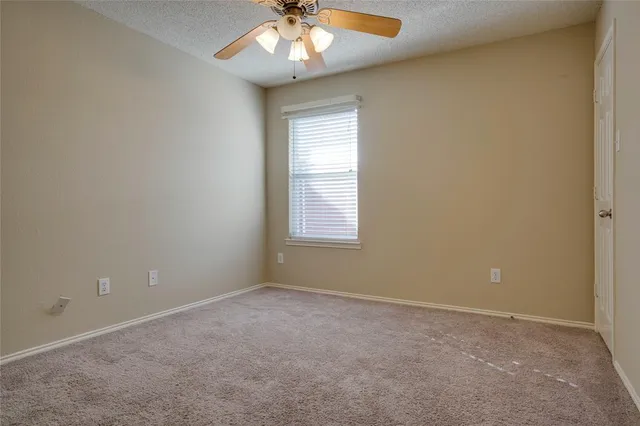 an empty room with a chandelier fan and windows