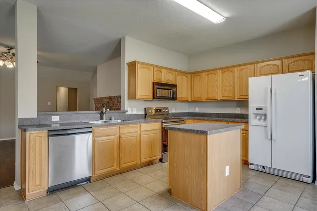 a kitchen with stainless steel appliances granite countertop a refrigerator and a stove top oven