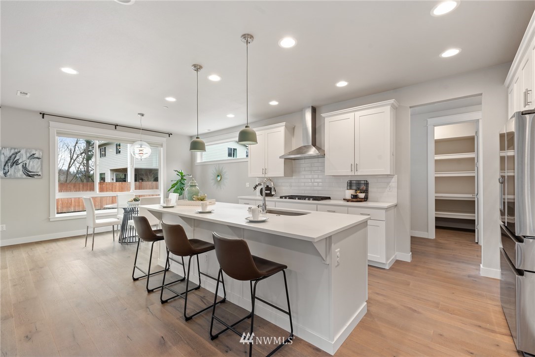 23417 26th Avenue Southeast Bothell, WA 98021 - Photo 12 of 40 a kitchen with stainless steel appliances a dining table chairs stove a sink and a refrigerator