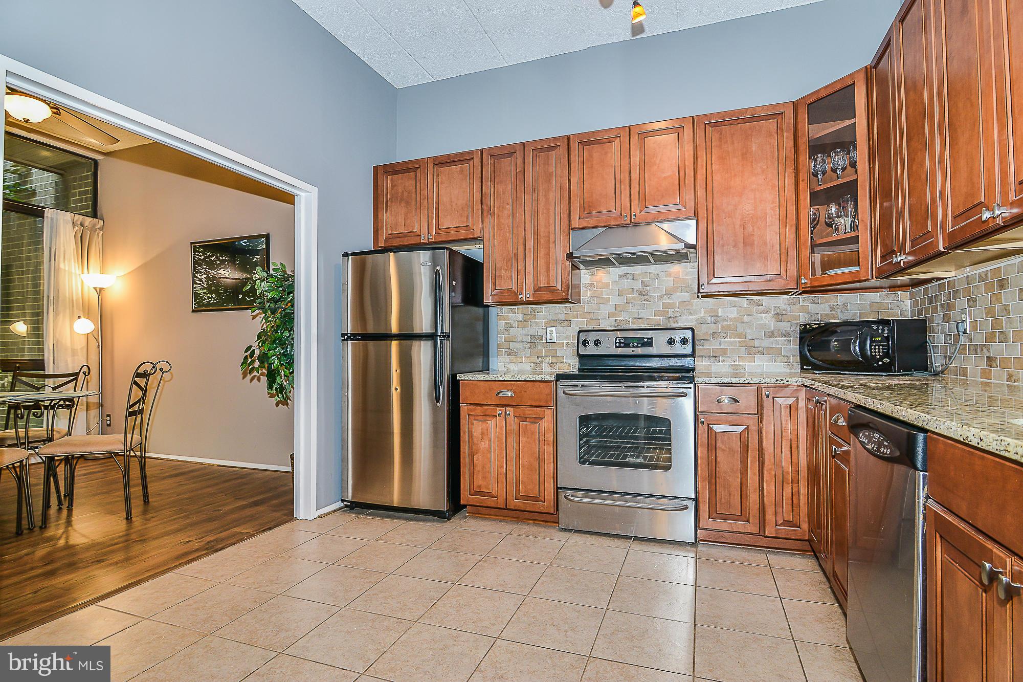 11620 Ivystone Court, Unit 101 Reston, VA 20191 - Photo 13 of 20 a kitchen with granite countertop a refrigerator stove top oven and cabinets