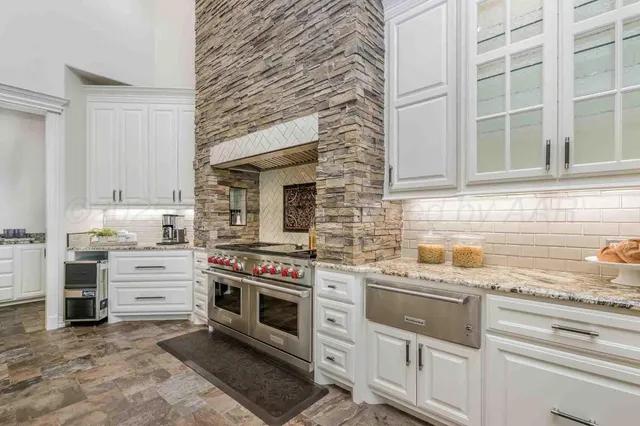 a kitchen with stainless steel appliances granite countertop white cabinets and a sink