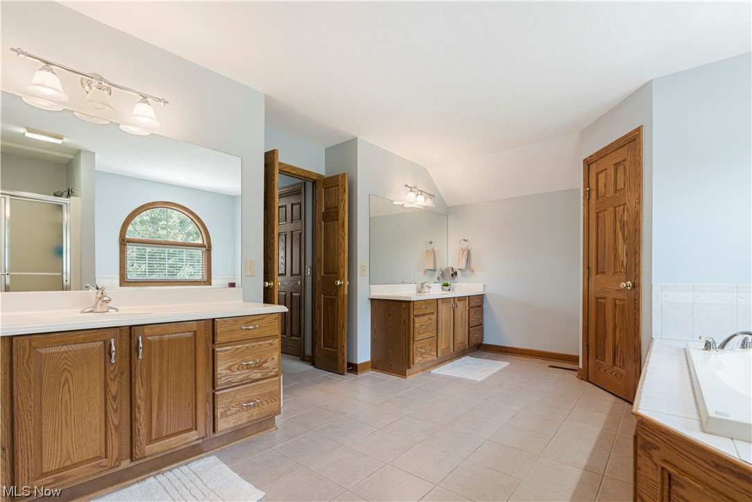 939 Pontius Road Mogadore, OH 44260 - Photo 21 of 35 Bathroom with dual bowl vanity, vaulted ceiling, separate shower and tub, and tile flooring