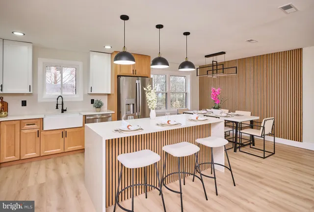 a kitchen island with stainless steel appliances kitchen island granite countertop a table chairs in it and wooden floors