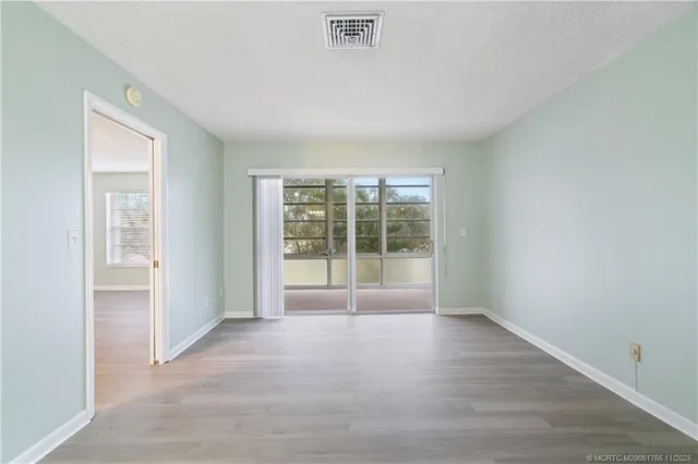 a view of a hallway with wooden floor and a bathroom