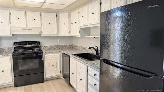 a kitchen with granite countertop white cabinets and refrigerator