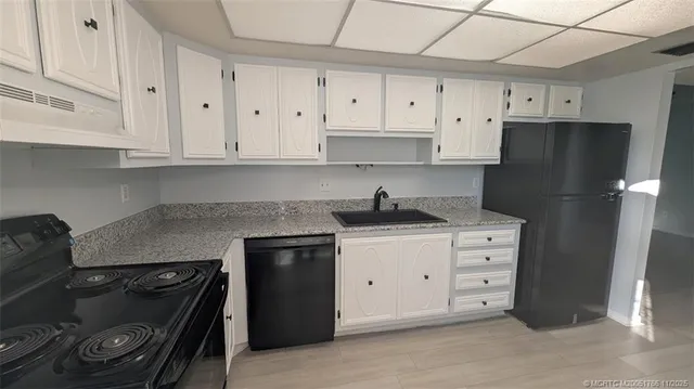 a kitchen with granite countertop white cabinets and refrigerator