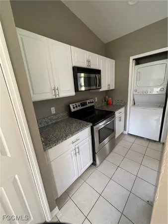 a kitchen with granite countertop a sink a stove top oven and cabinetry