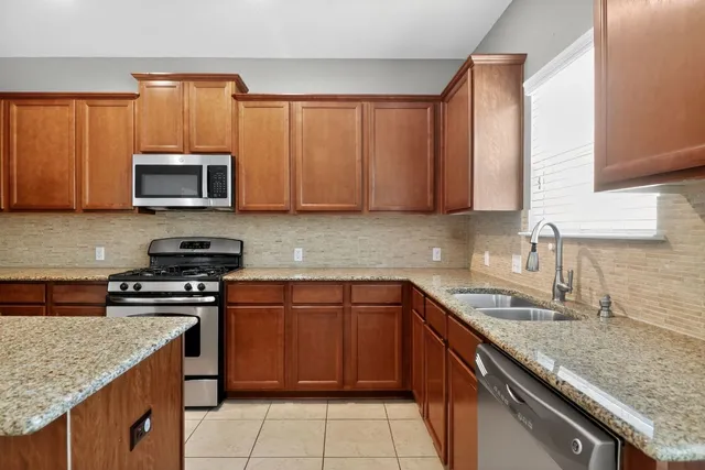 a kitchen with stainless steel appliances granite countertop a refrigerator and a stove top oven