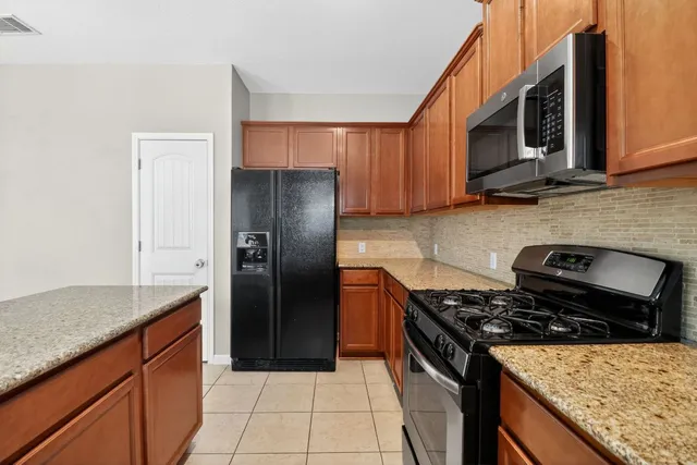 a kitchen with stainless steel appliances granite countertop a stove a sink and a microwave