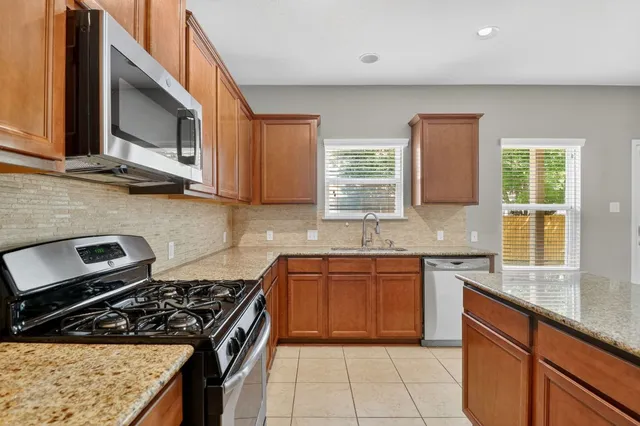 a large kitchen with stainless steel appliances granite countertop a refrigerator and a sink