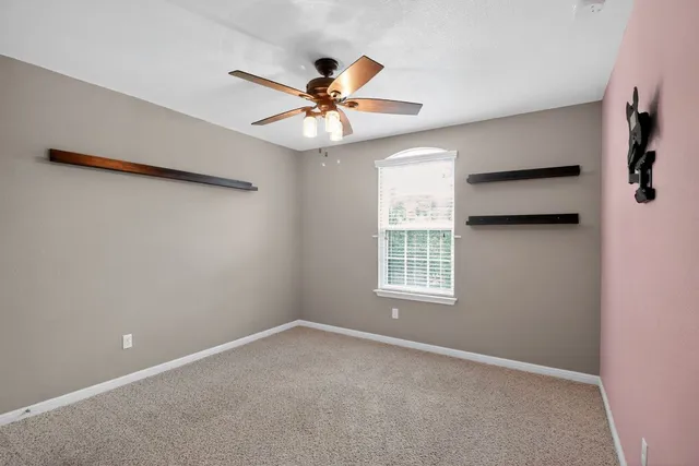 an empty room with a window and a fan