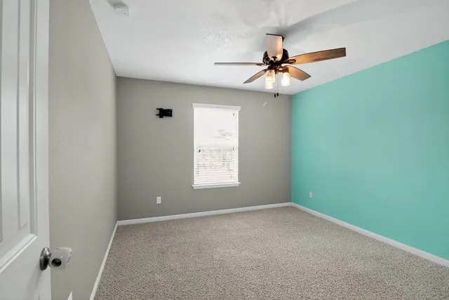 an empty room with windows and fan