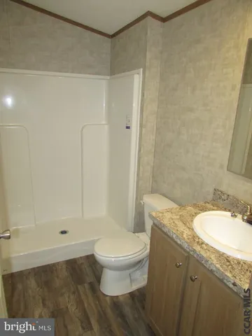 a bathroom with a granite countertop sink a toilet and shower