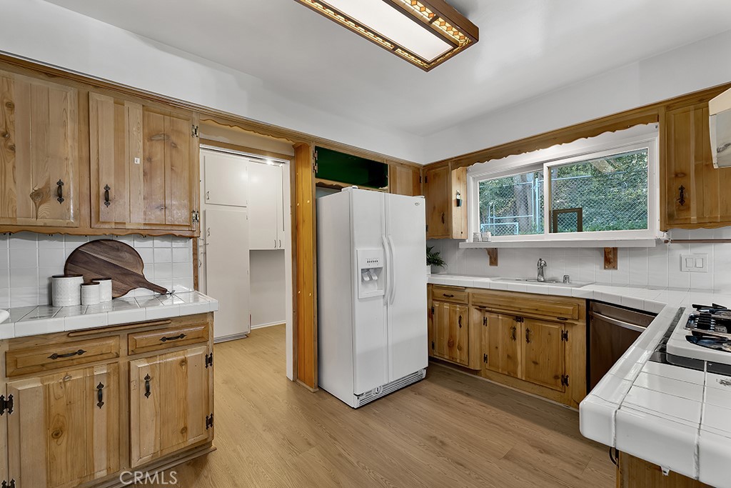 4775 Regalo Road Woodland Hills, CA 91364 - Photo 21 of 42 a kitchen with stainless steel appliances granite countertop a refrigerator a sink dishwasher a stove and white countertops with wooden floor