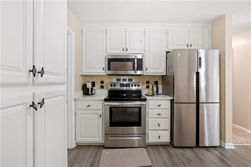 1300 Sunflower Court Locust Grove, GA 30248 - Photo 10 of 24 a kitchen with stainless steel appliances white cabinets and a refrigerator