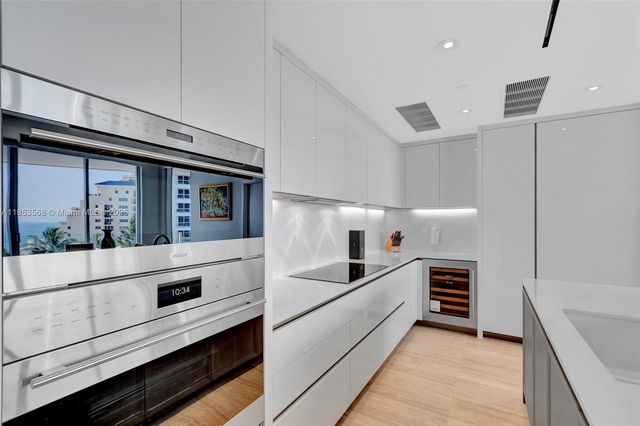a large white kitchen with sink and stainless steel appliances