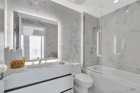 a bathroom with a bathtub shower sink vanity mirror and toilet
