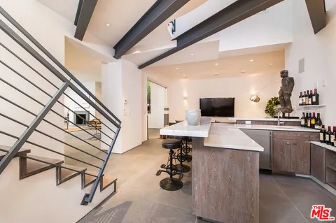 a kitchen with stainless steel appliances kitchen island granite countertop a sink dishwasher stove and white cabinets with wooden floor