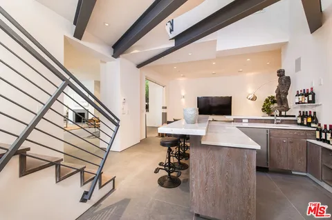 a kitchen with stainless steel appliances kitchen island granite countertop a sink dishwasher stove and white cabinets with wooden floor